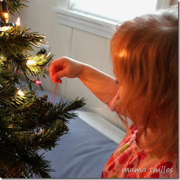 Lily hangs a Christmas tree ornament